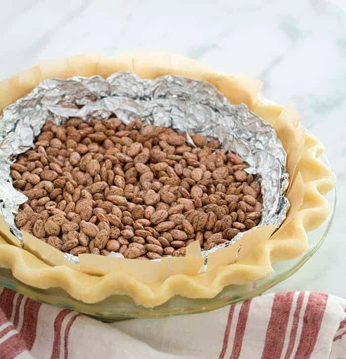 An unbaked pie crust filled with foil and beans