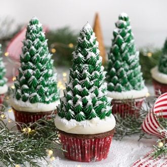 A photo of three Christmas tree cupcakes on a white marble table.