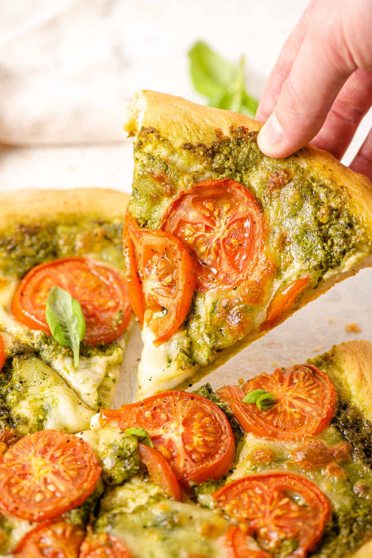 A close up of a hand picking up a slice of pizza