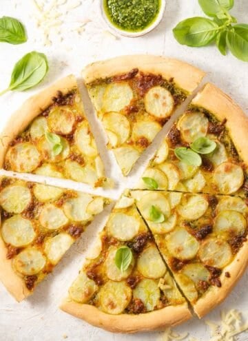 An overhead shot of a potato pizza cut into slices