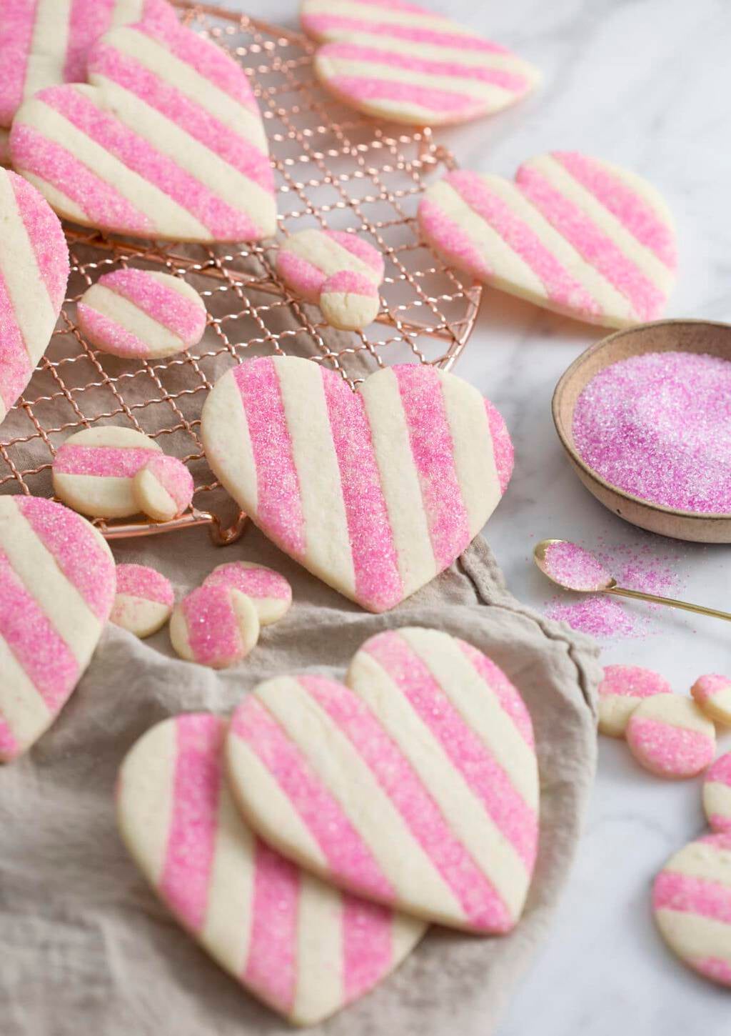 A photo showing a group of striped pink and white Valentine's Day Heart Cookies on a white marble surface