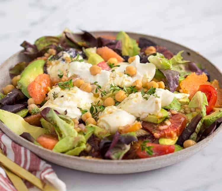 an avocado salad with chick peas and fresh thyme on a marble table