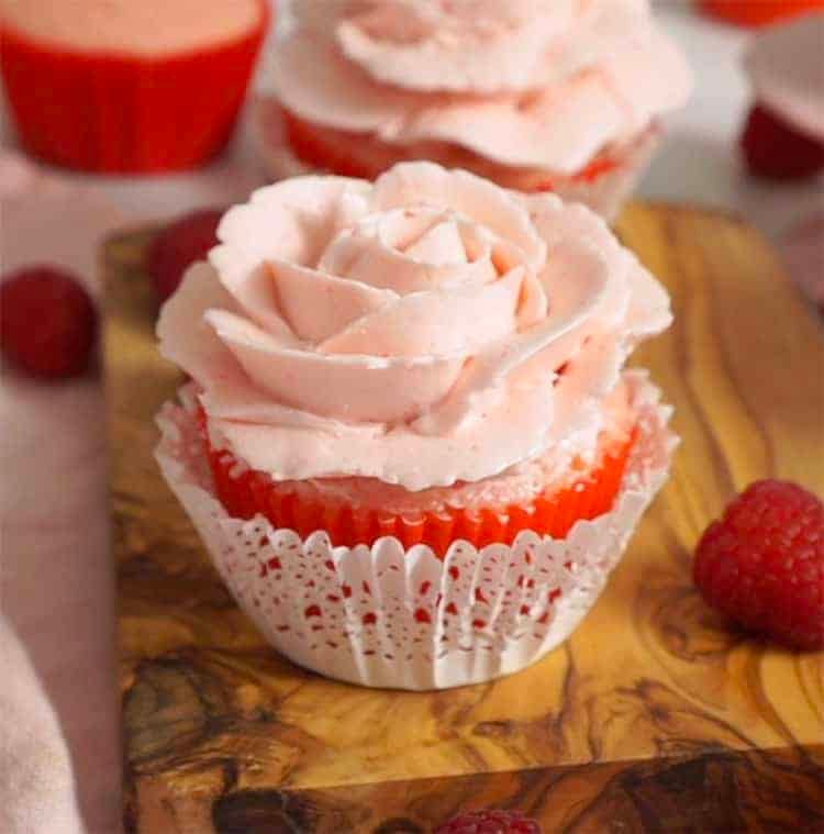 A pink buttercream rose on a valentine cupcake.
