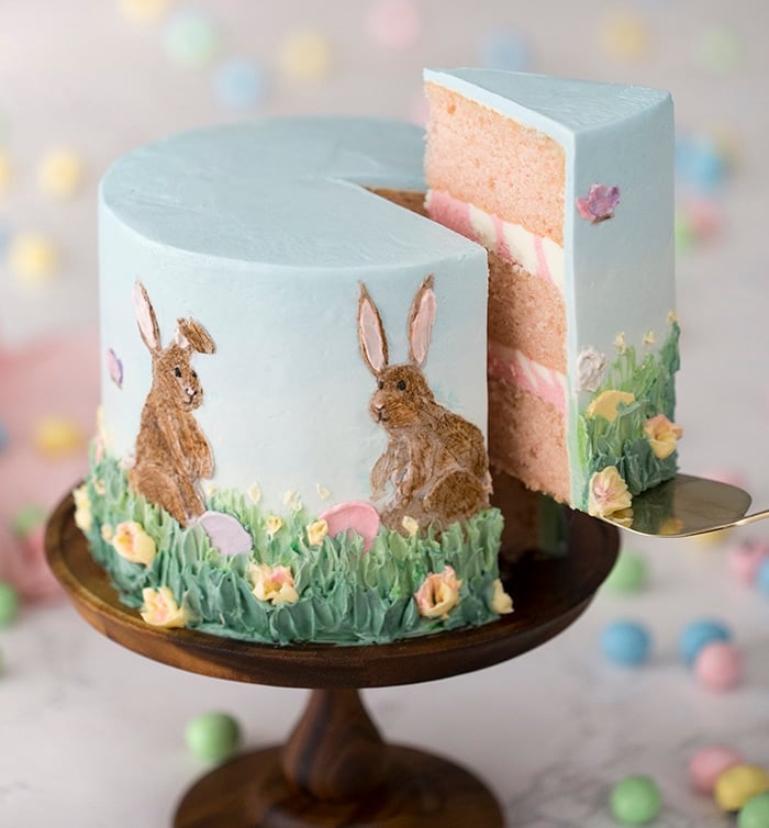 A photo of an Easter cake with a piece being removed.
