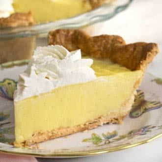 a piece of vanilla cream pie topped with whipped cream on a porcelain plate