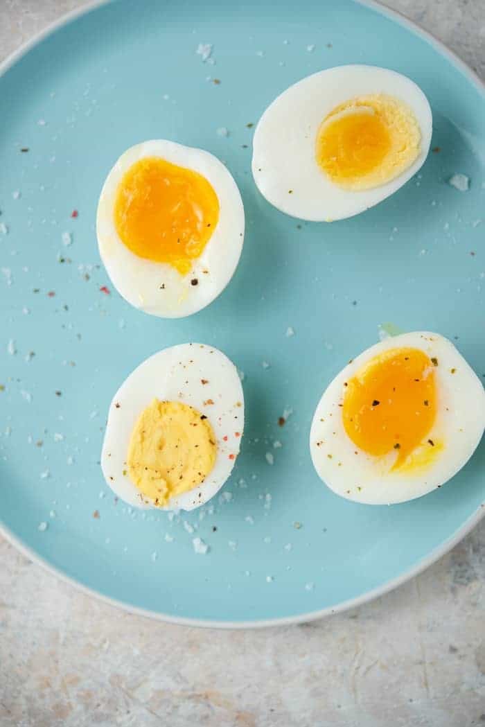Instant Pot Hard Boiled Eggs plus how to make soft boiled and jammy eggs any way you like. The instant pot makes boiling eggs to your liking super easy, no more keeping an eye on the timer! #eggs #instantpot An overhead shot of instant pot hard boiled eggs and soft boiled eggs on a blue plate