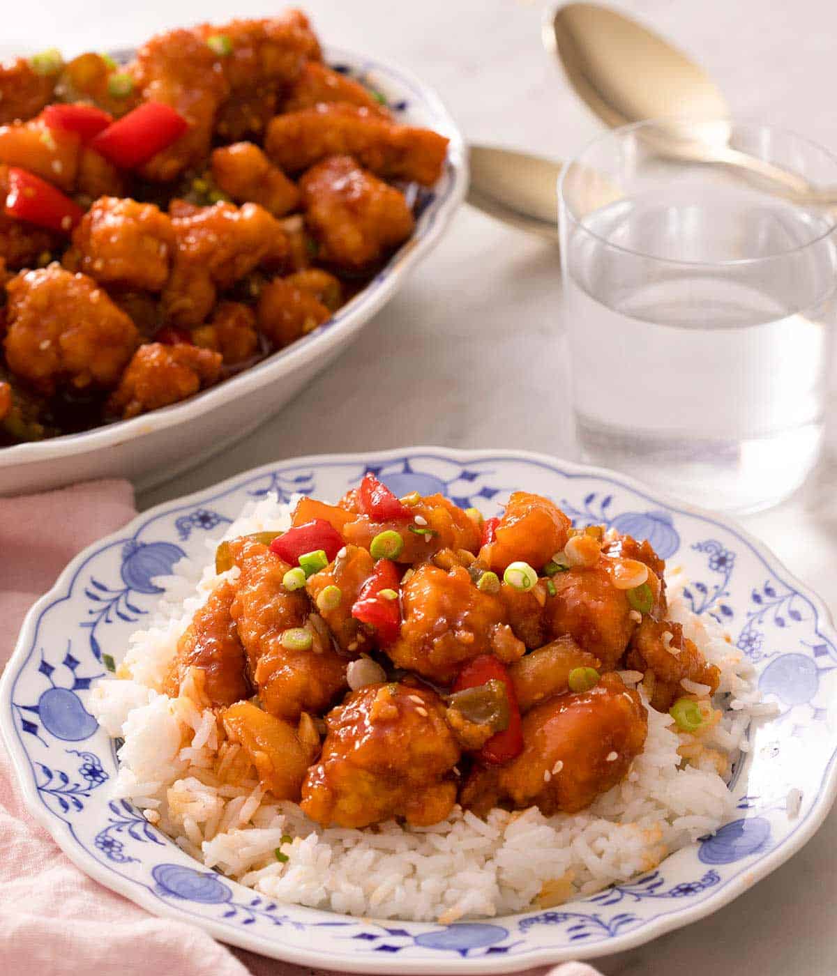 A blue plate with rice and sweet and sour chicken on top