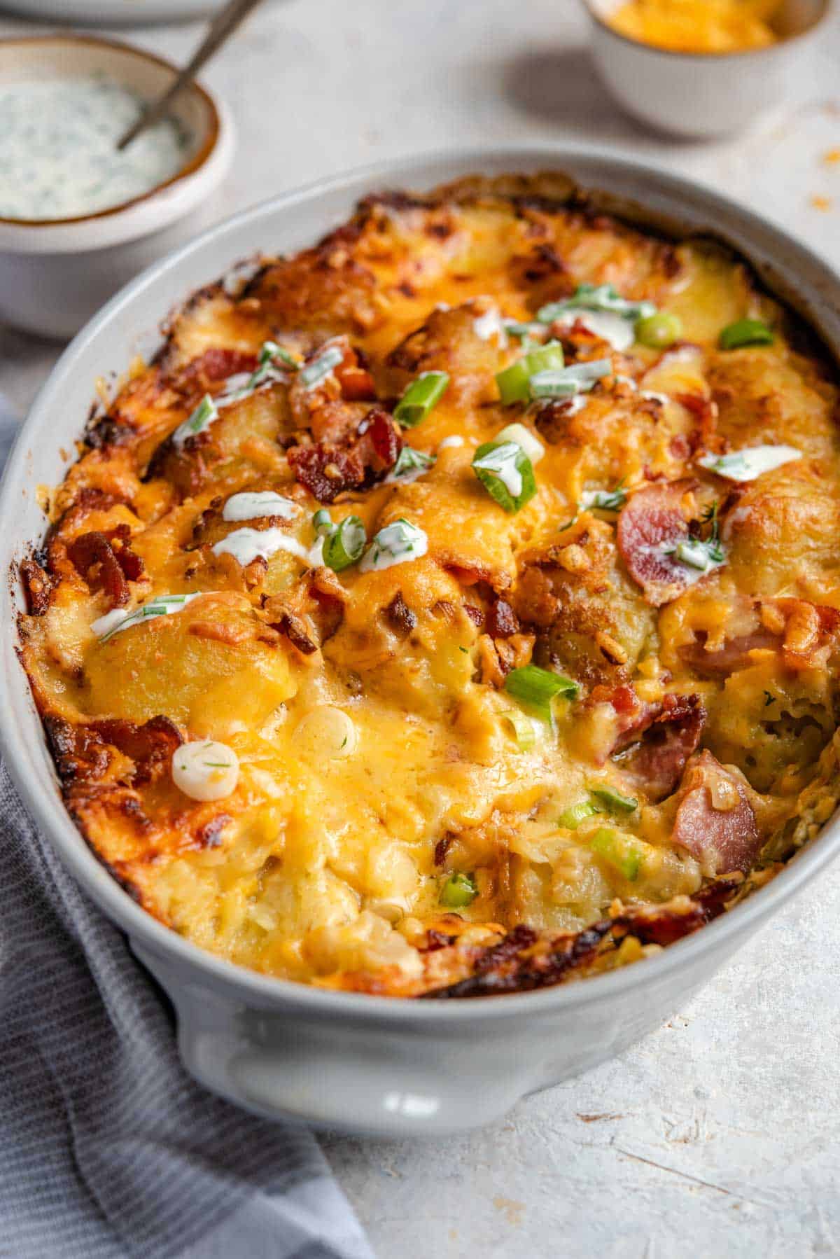 Insanely delicious Tater Tot Casserole that's loaded with crispy bacon and cheesy goodness. If you love loaded potato skins this casserole will be your new favorite thing. Super easy and a family favorite! #tatertot #casserole #comfortfood A close up of a cheesy tater tot casserole in a baking dish
