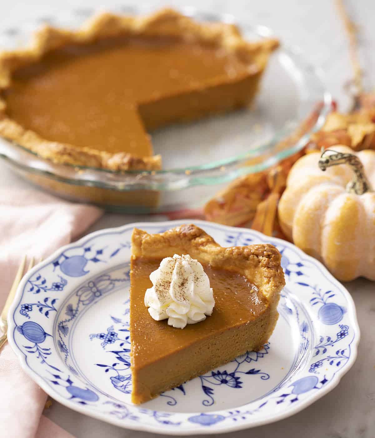 A piece of pumpkin pie with whipped cream on top.