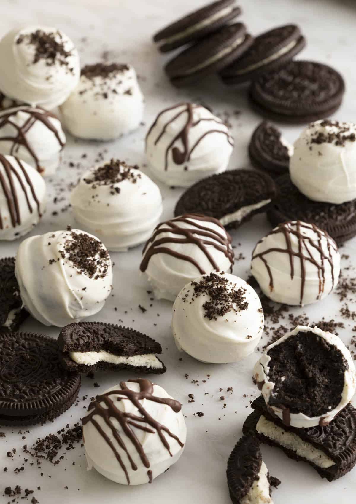 Several oreo balls and oreos scattered across a white counter.