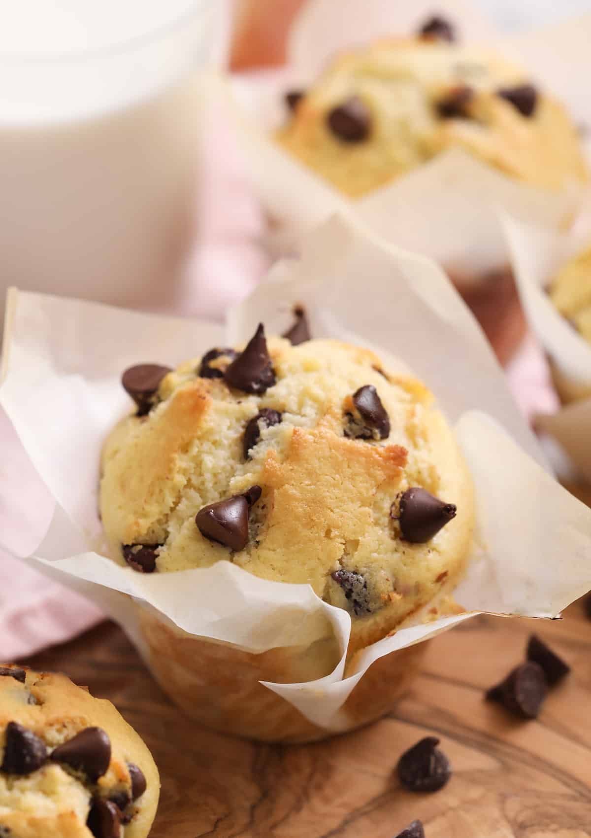 Chocolate Chip Muffins on a wooden board next to a glass of milk.