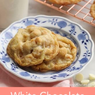 Pinterest graphic showing two white chocolate macadamia cookies on a plate next to a glass of milk.