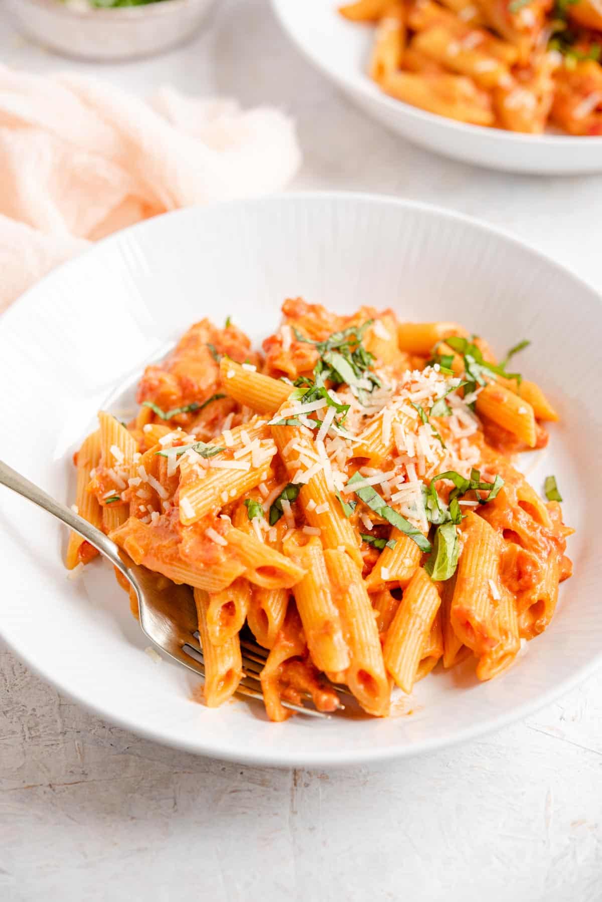 A side shot of penne alla vodka in a bowl topped with herbs and cheese