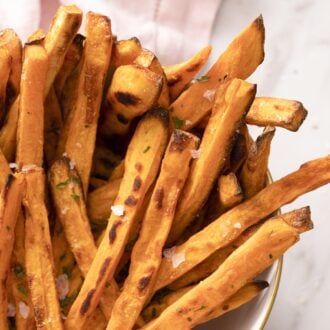 Sweet potatoe fries with sea salt in a white bowl.