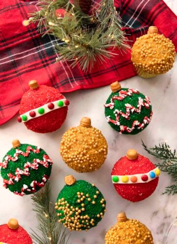 A group of cupcakes decorated as colorful Christmas ornaments.
