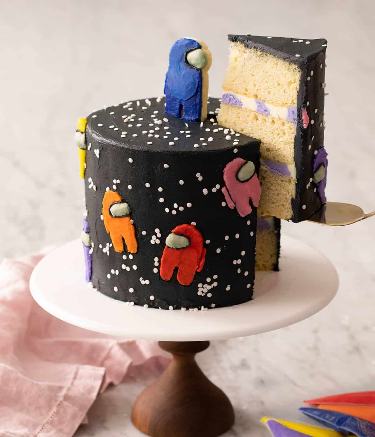 Among us cake on a cake stand with a big slice getting removed