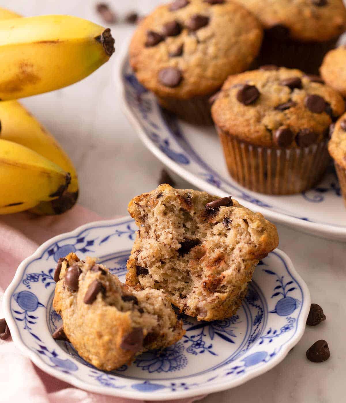 A banana chocolate chip muffin cut in half on a blue plate