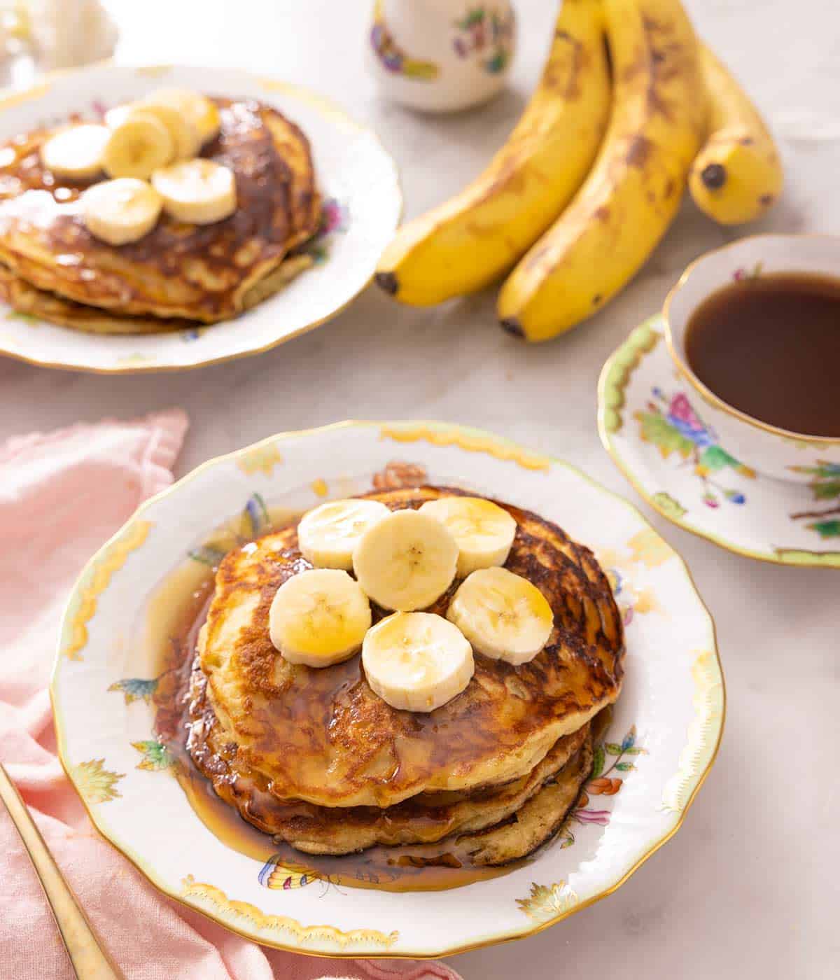 Banana pancakes on a plate topped with slices of banana.