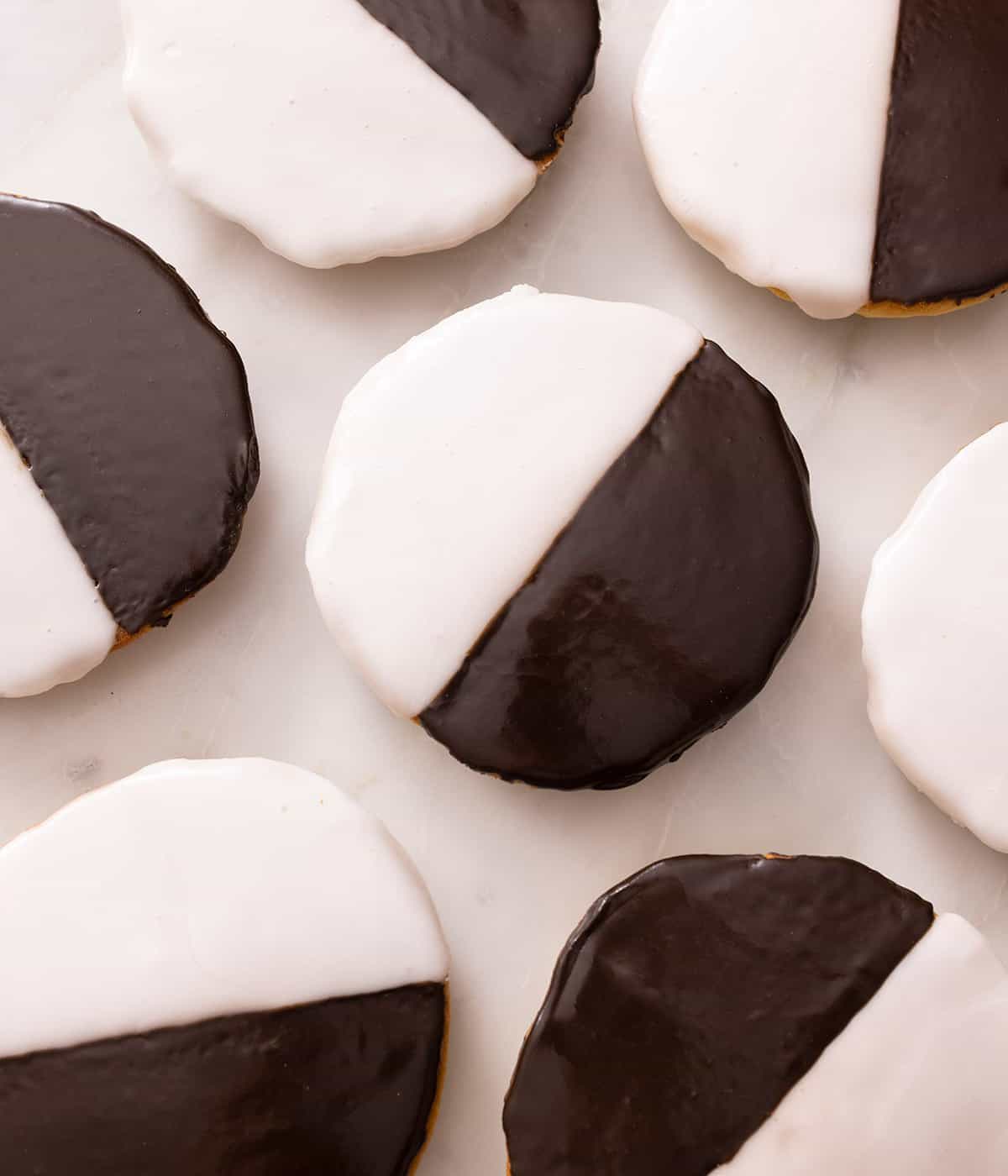 Overhead view of cookies that are half covered with vanilla icing and other half covered with chocolate icing.