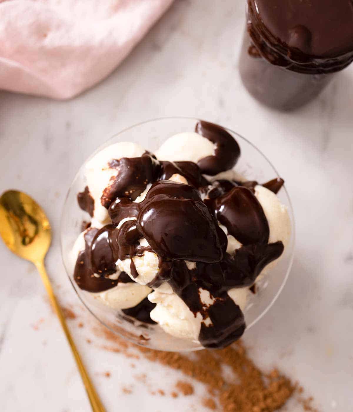 Overhead over of hot fudge over top of ice cream in a bowl.