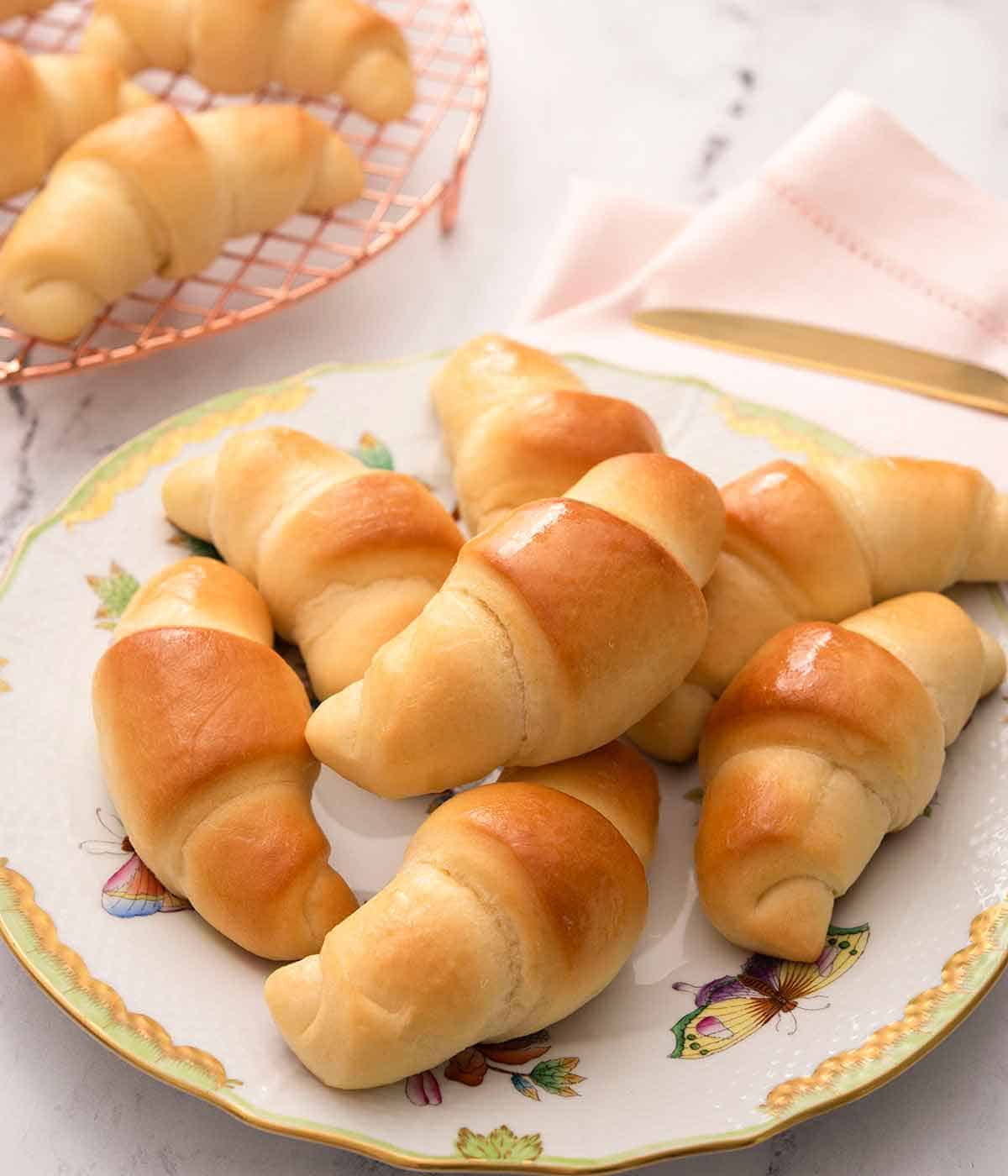 Close up of a plate of seven crescent rolls on a pink linen.