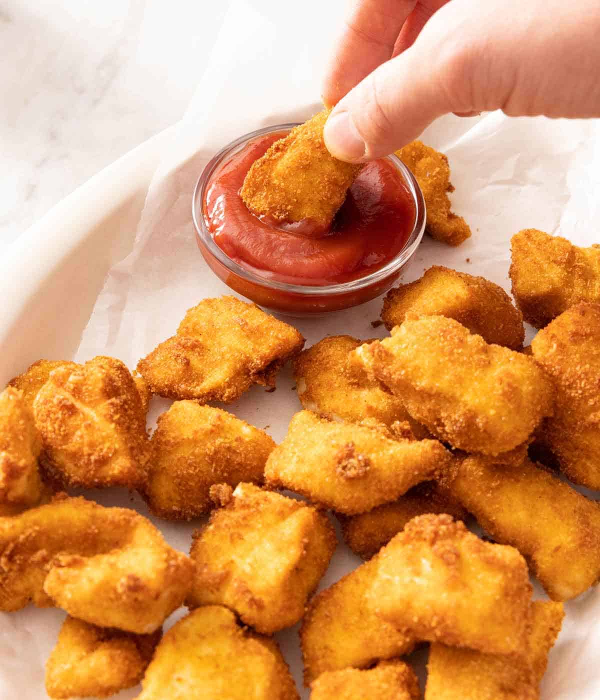 A piece of chicken nugget dipped into ketchup.