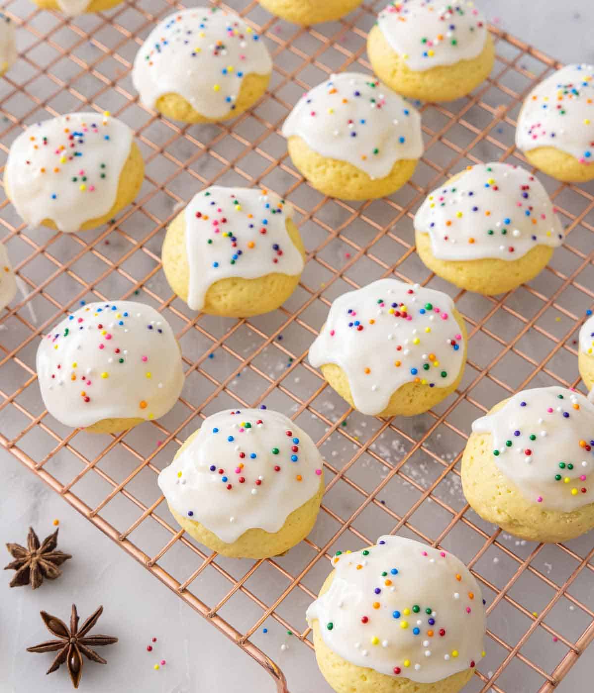 A cooling rack with anise cookies on top and some anise stars on the side.