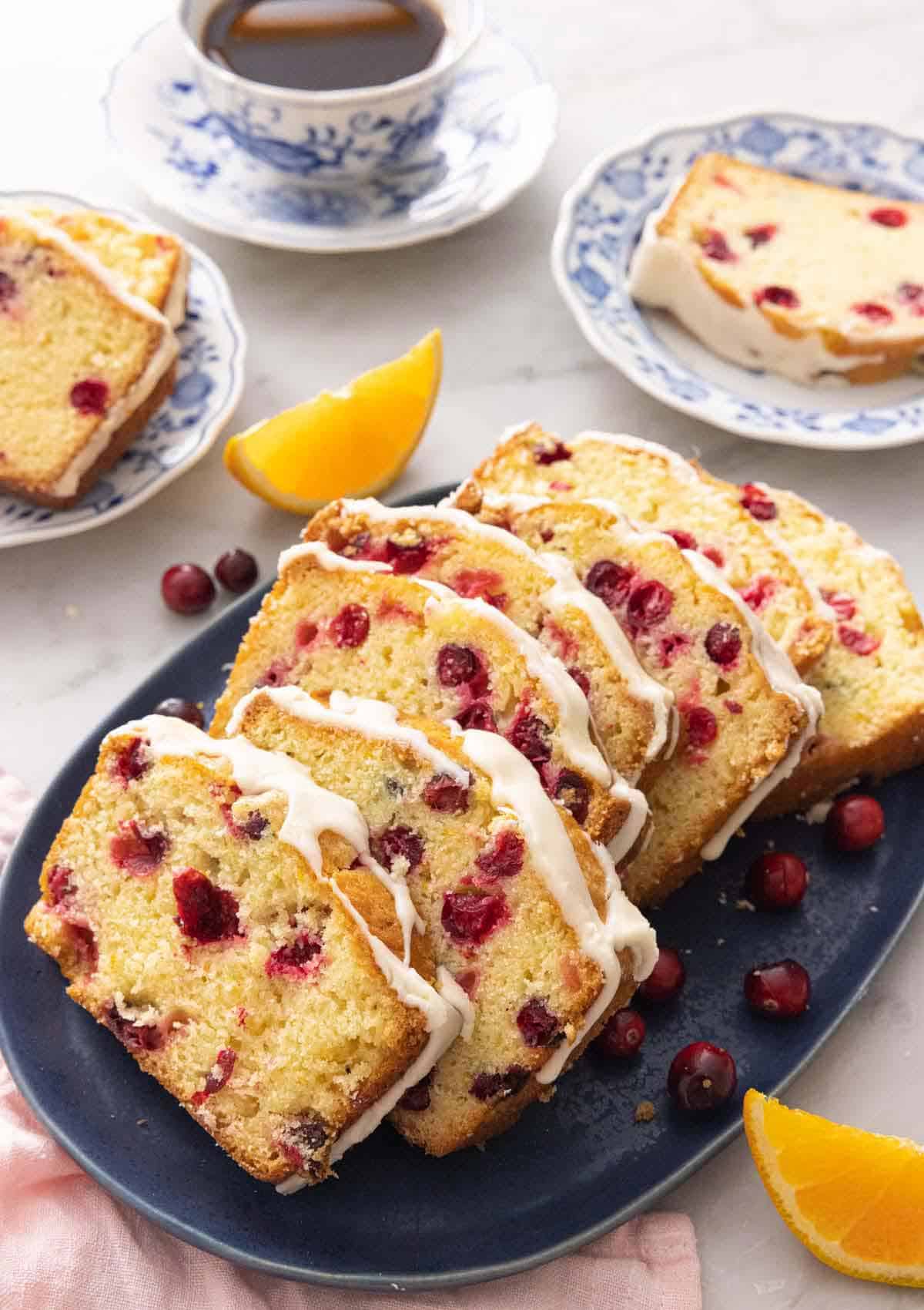 A platter with sliced cranberry orange bread with fresh fruit around it.