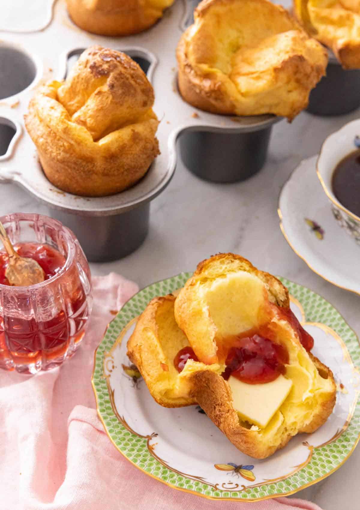 Half of a popovers with butter and jam spread in the middle.