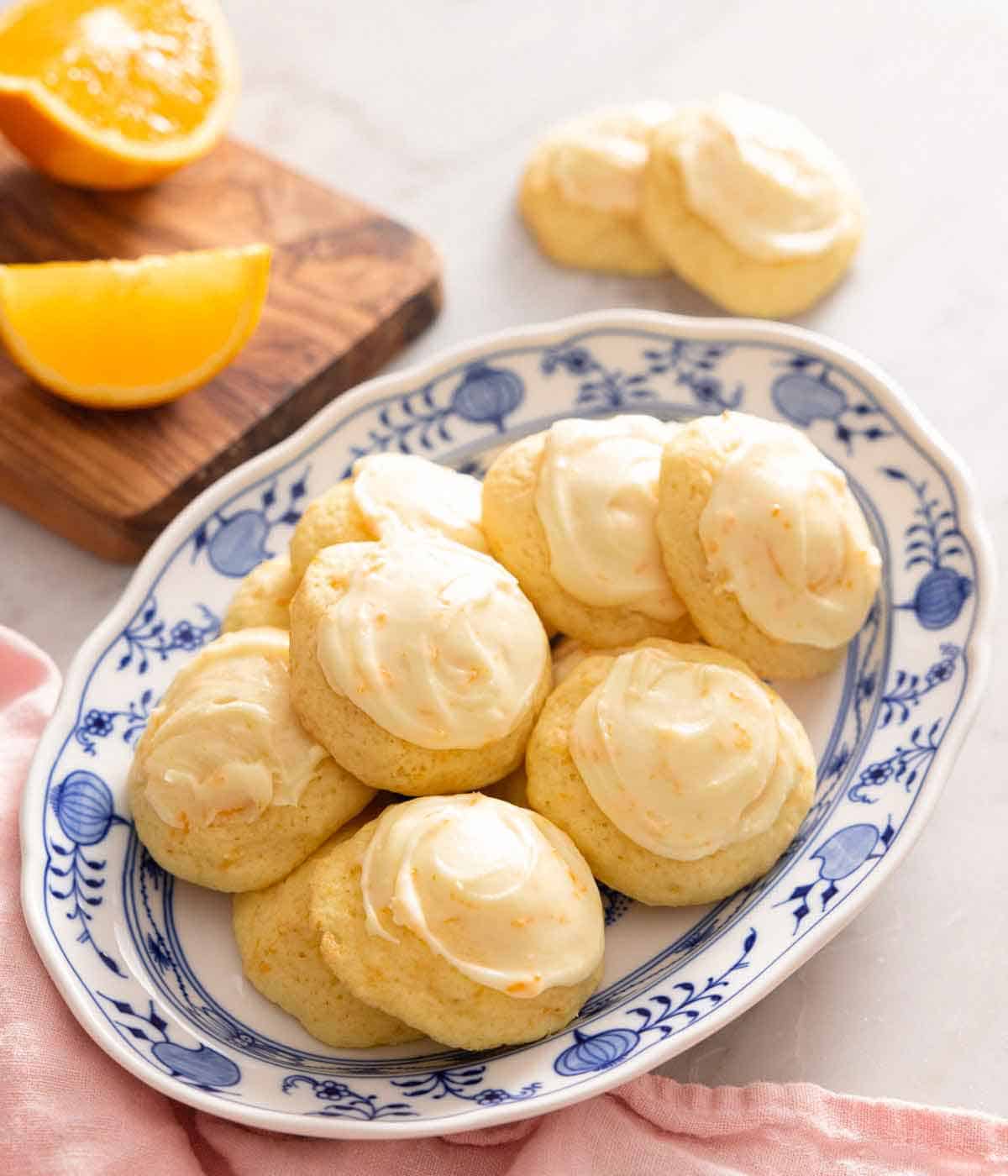 A platter of orange cookies with orange wedges in the background.