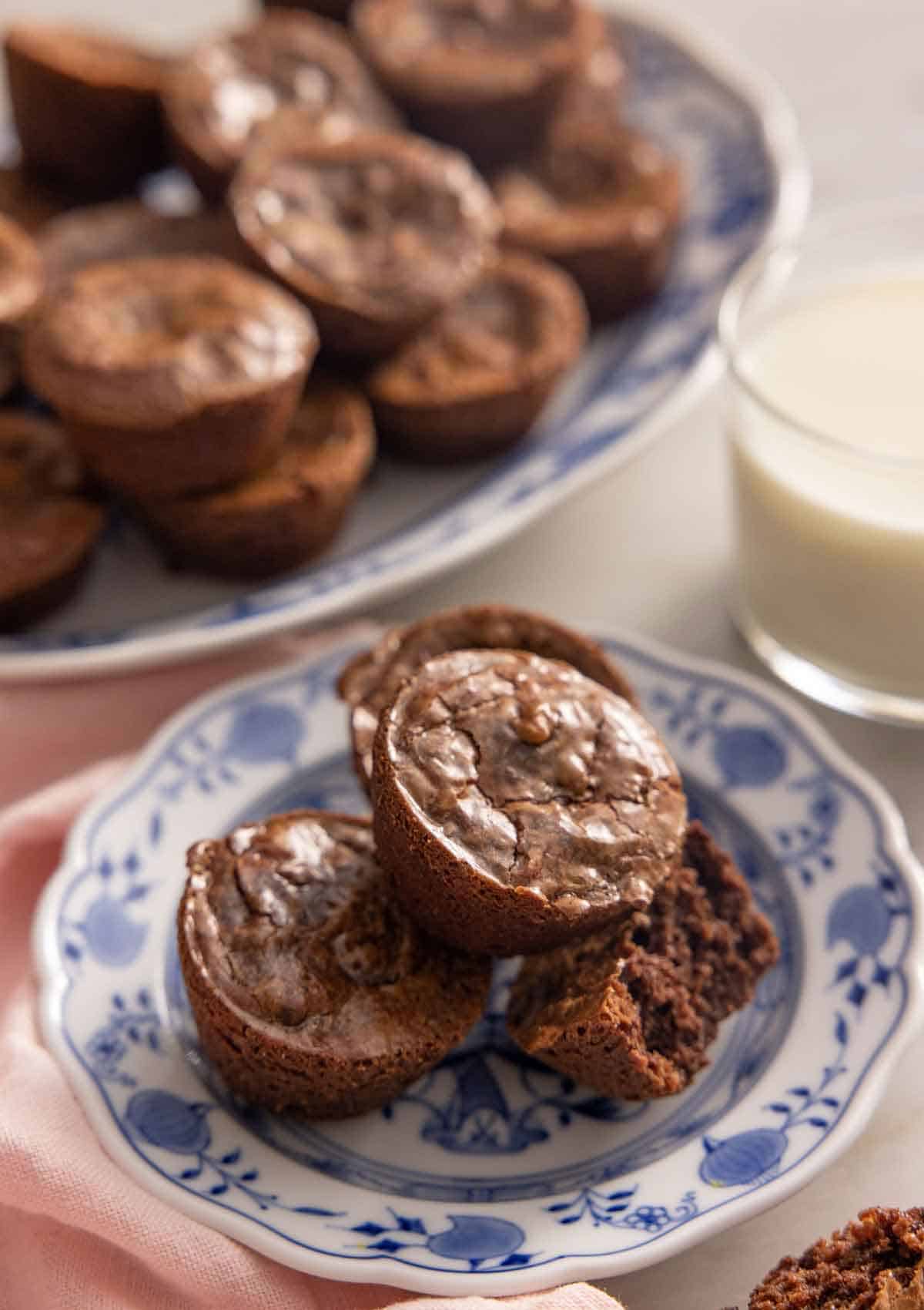 A plate with a stack of brownie bites, one with a bite taken out.