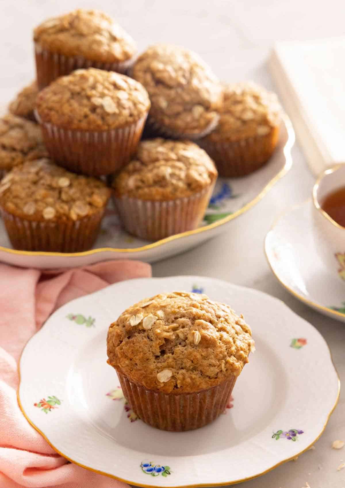 A plate with an oatmeal muffin with a platter in the back.