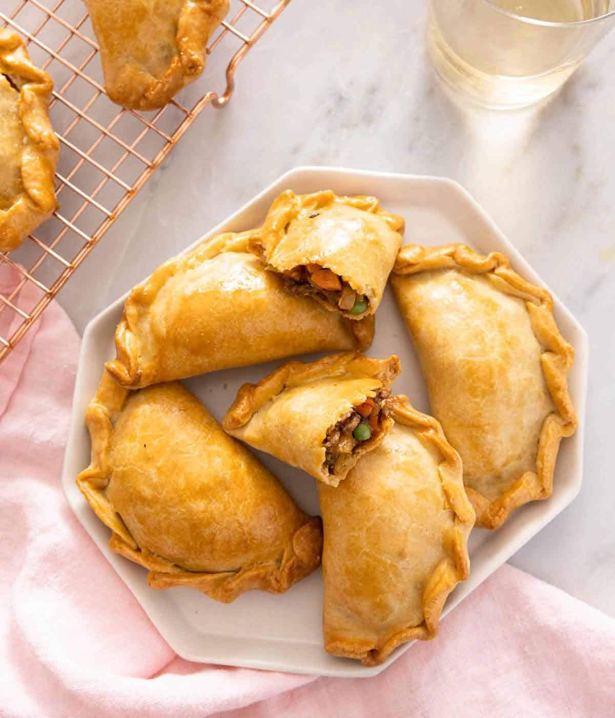 A platter of empanadas with one cut open.