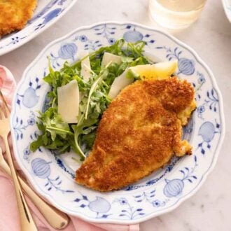 Overhead view of a plate of chicken Milanese with salad on the side.