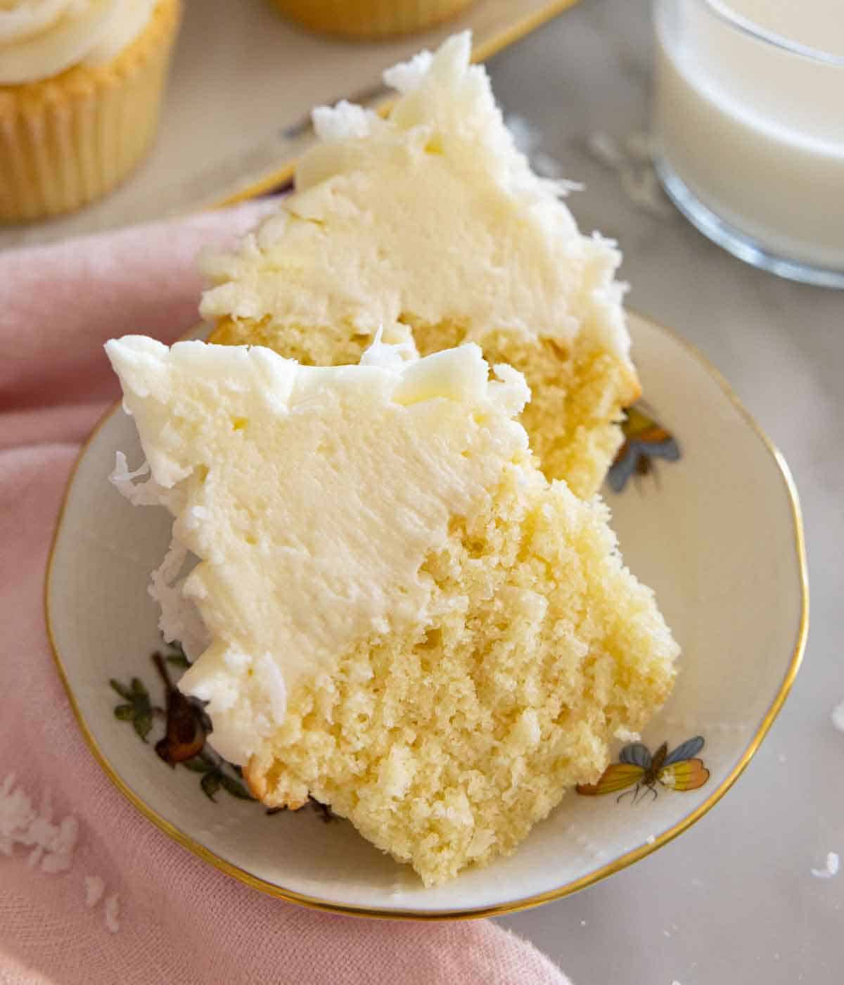 A coconut cupcake cut in half, on a small dessert plate.