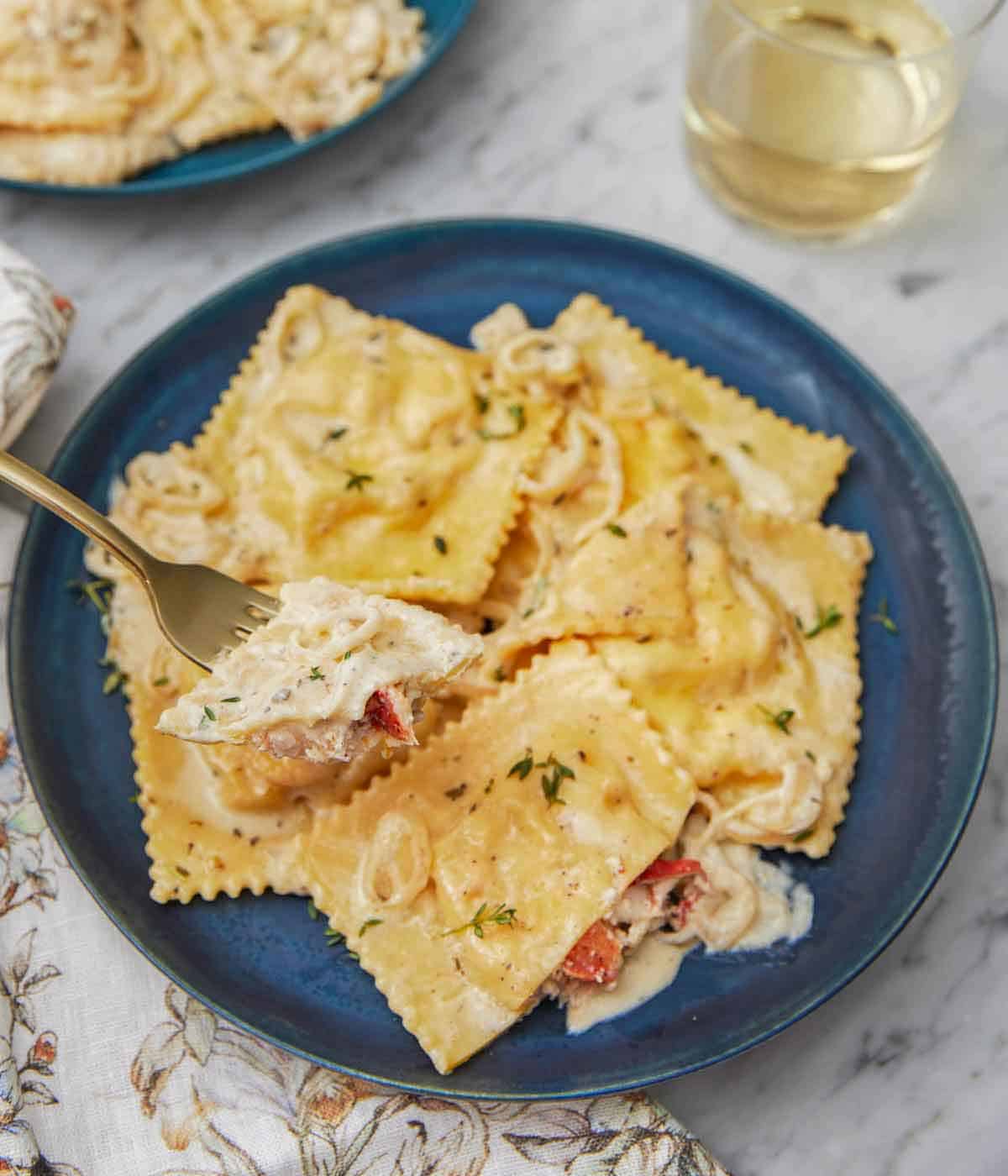 A plate of lobster ravioli with a fork lifting up a bite.