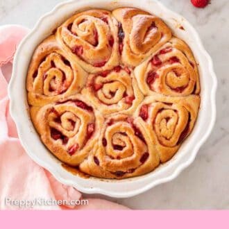 Pinterest graphic of an overhead view of strawberry rolls in a round white baking dish with four fresh strawberries beside it.