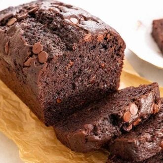 A loaf of chocolate zucchini bread with slices cut in front of it.
