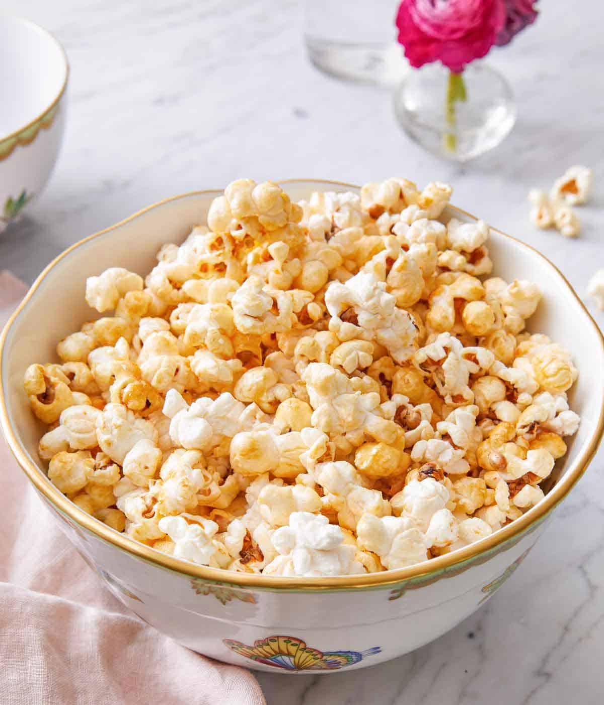 A bowl of kettle corn by a pink linen napkin.