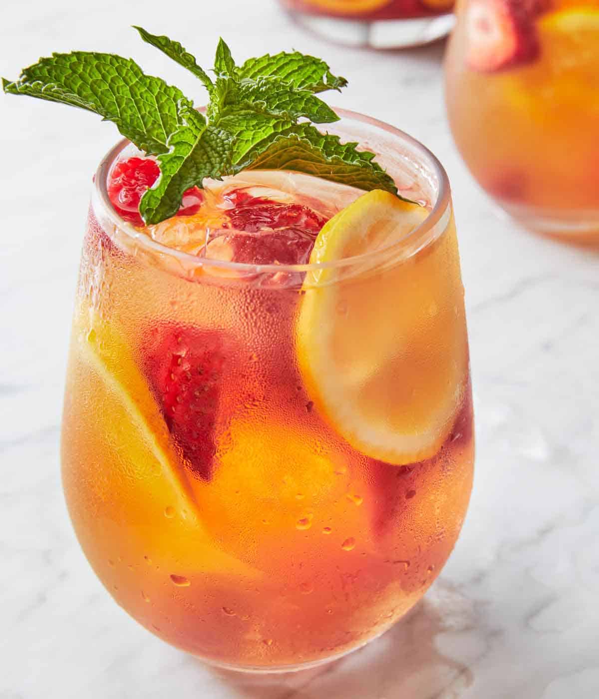 A slightly angled view of a glass of rose sangria with mint on top.