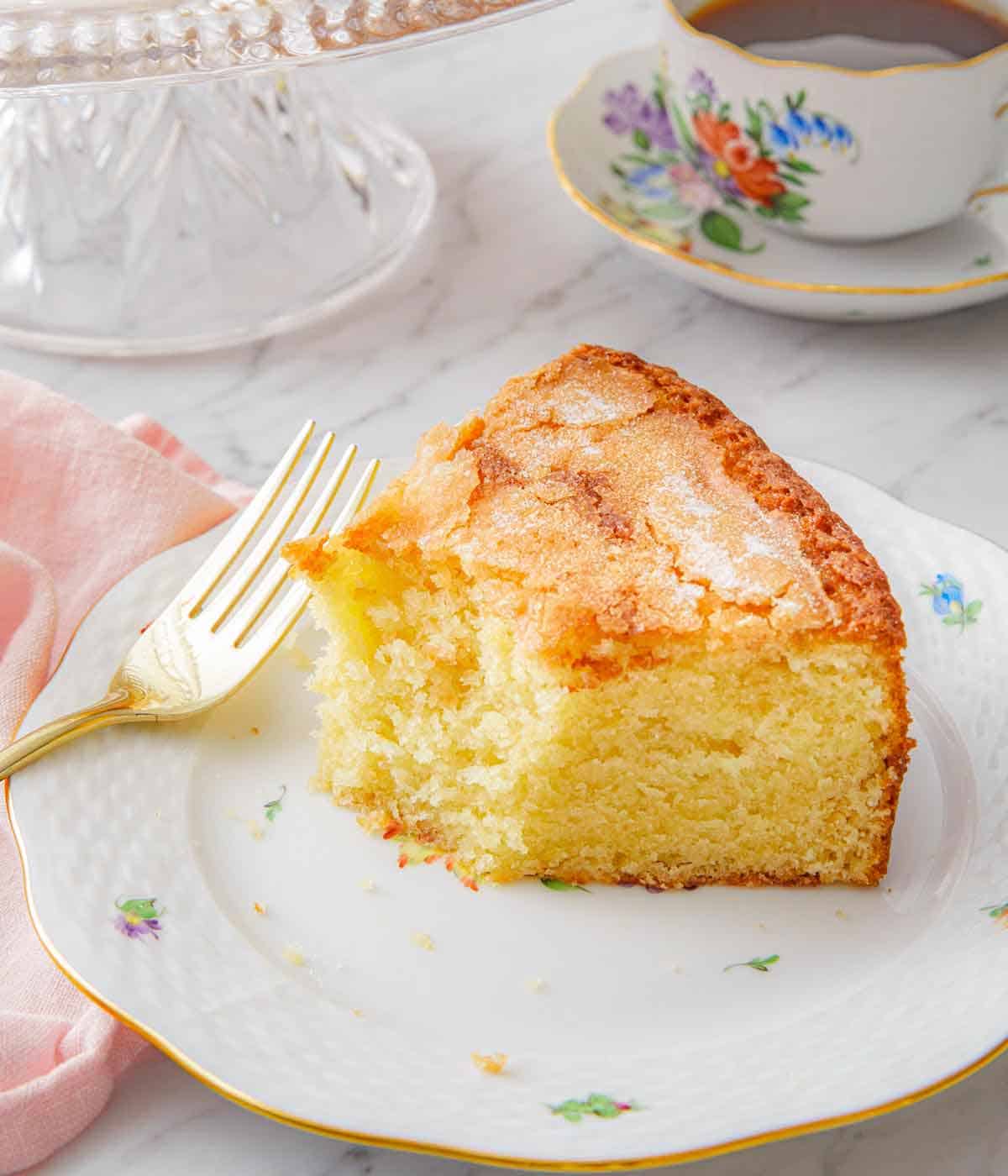 A plate with a slice of olive oil cake with half of it eaten.