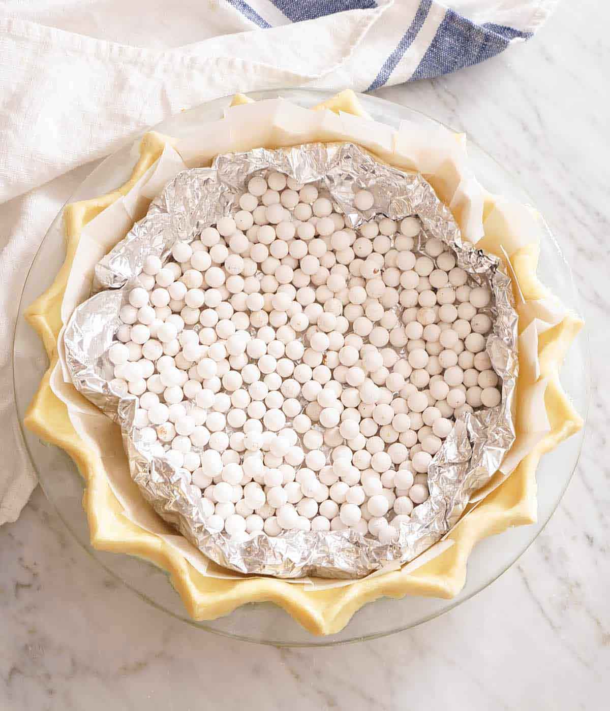 Overhead view of pie crust rough in a pan with pie weights.