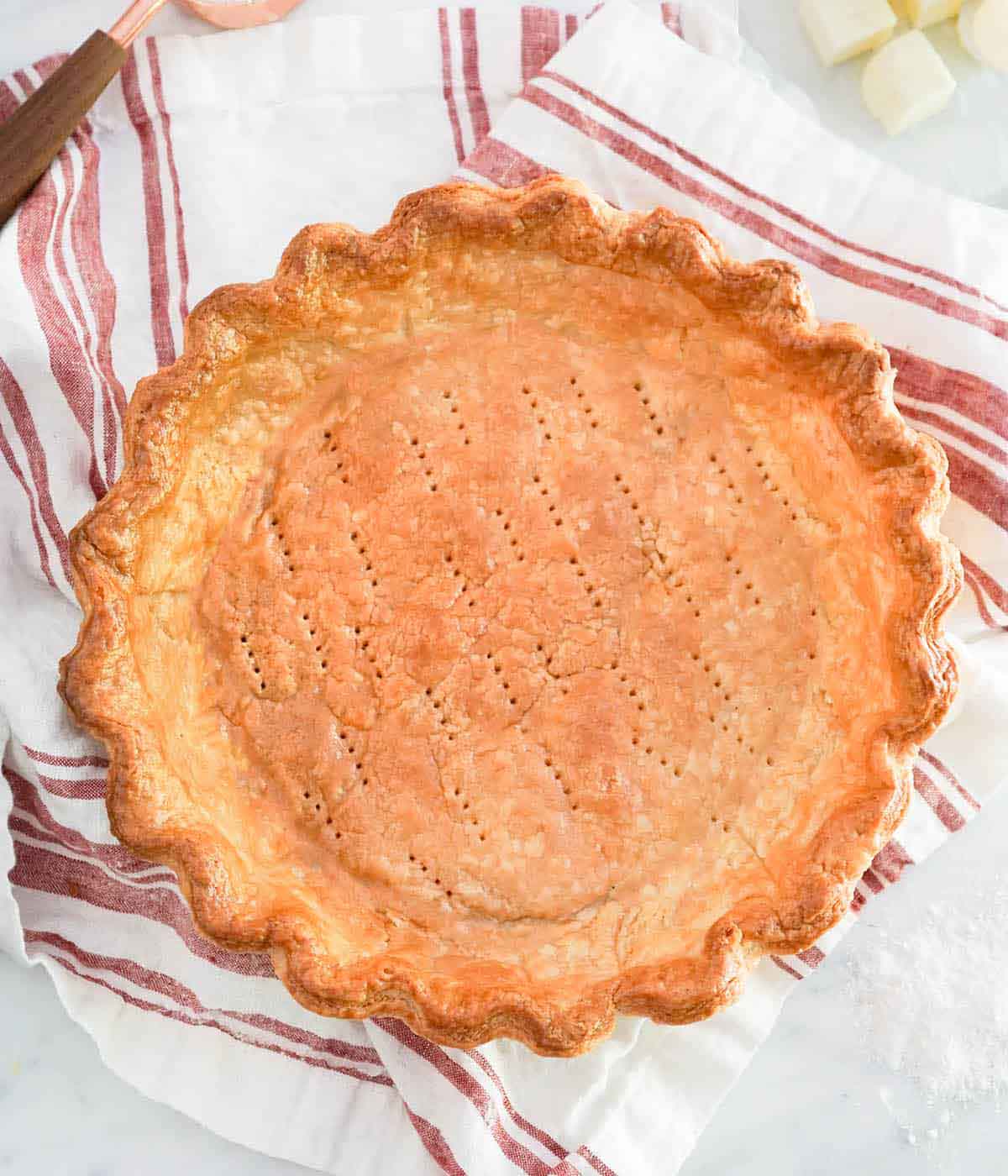 Overhead view of a baked pie crust with docking marks.