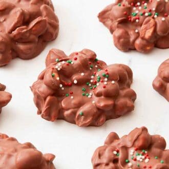 A marble surface with multiple pieces of crockpot candy with a couple with sprinkles on it.