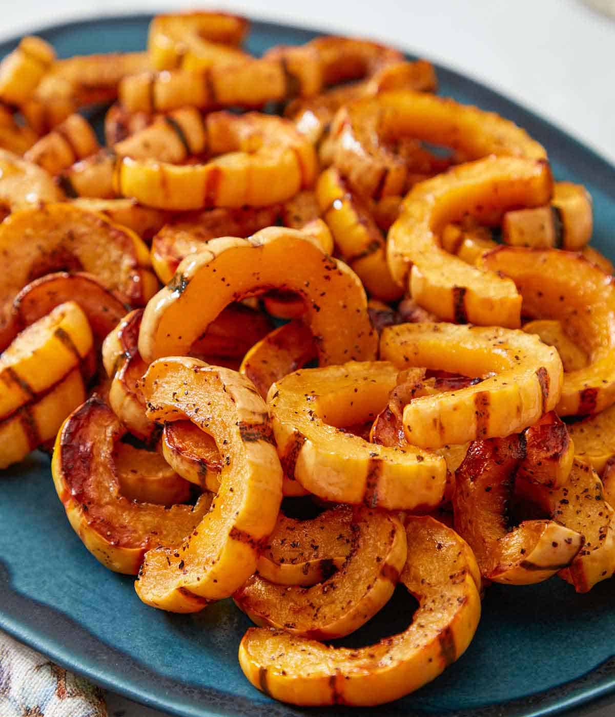 Close up view of a blue serving platter of roasted delicata squash.