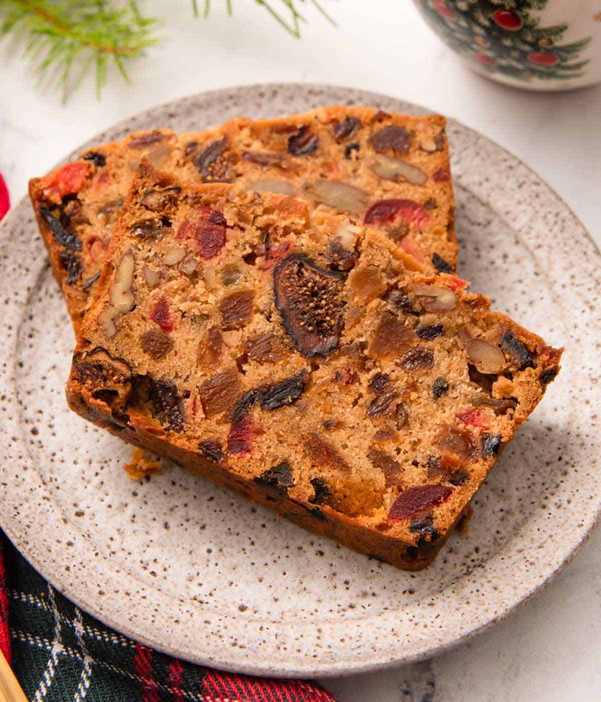 A plate with two slices of fruit cake, one stacked on top of the other.
