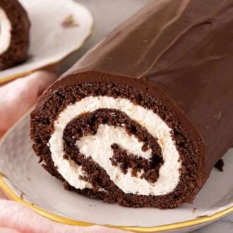 Close up of a platter with a Swiss roll with the front slice cut off.