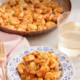 Pinterest graphic of a plate of sautéed shrimp with a glass of wine and skillet on shrimp in the background.