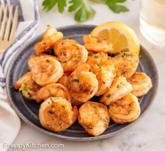 Pinterest graphic of a plate of sautéed shrimp with a slice of lemon. Wine and parsley in the background.