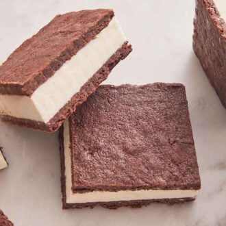 Multiple ice cream sandwiches on a marble surface with one slightly stacked on another.